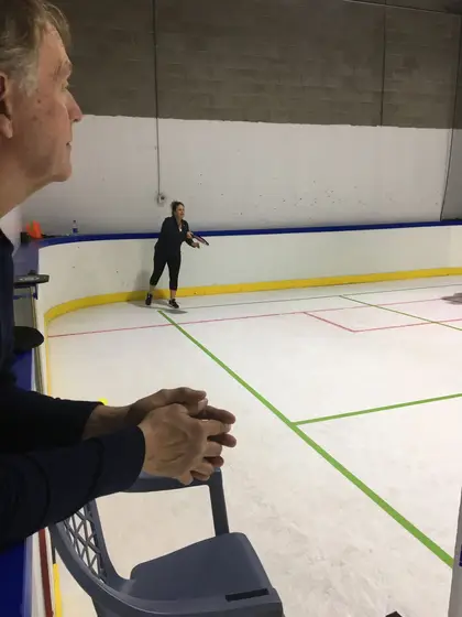 A spectator watching the pickleball league from the boards